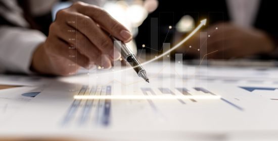Two businessmen are meeting together, they point to financial do Two businessmen are meeting together, they point to financial documents to discuss plans and solutions, chart graphics showing financial status and performance. Business administration concept.